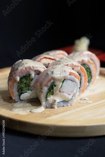 Sushi roll with salmon, cheese and avocado. Maki roll with shrimps fried, avocado and lattuce on a wooden plate . Delicious sushi rolls served on grey table