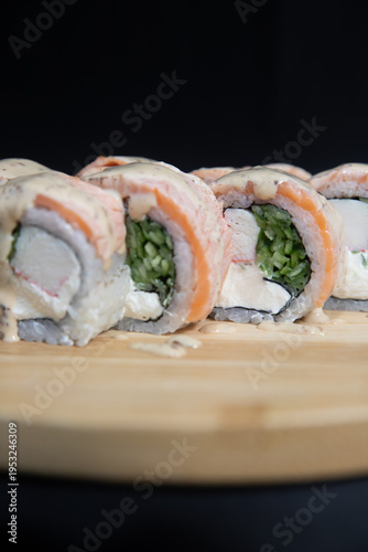 Sushi roll with salmon, cheese and avocado. Maki roll with shrimps fried, avocado and lattuce on a wooden plate . Delicious sushi rolls served on grey table