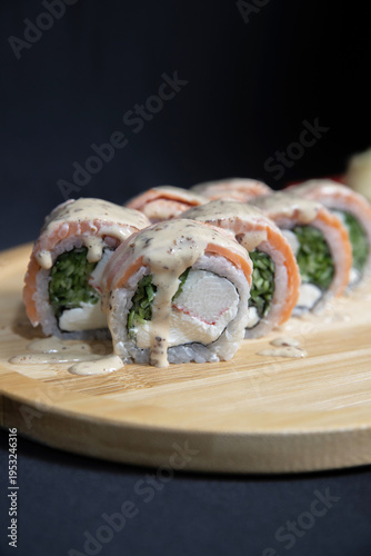 Sushi roll with salmon, cheese and avocado. Maki roll with shrimps fried, avocado and lattuce on a wooden plate . Delicious sushi rolls served on grey table