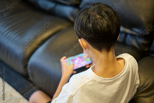 スマホゲームに夢中の男の子の後ろ姿