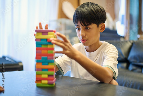 ジェンガのブロックを慎重に抜く男の子