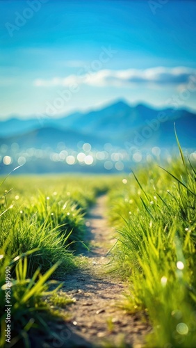 A photo of a serene grass path isolated against a clear blue sky with distant hills in the background, rendering the scene with sharp focus and natura