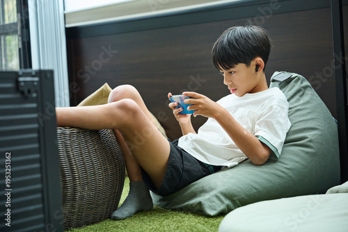 ビーズクッションに座りスマホを操作する男の子