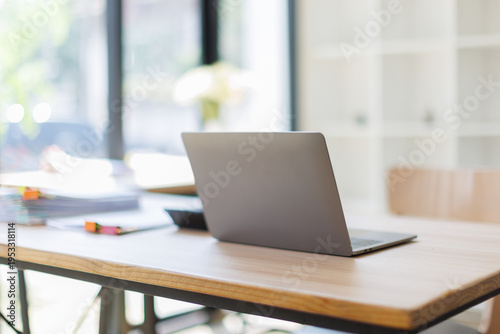 A clean and minimalistic workspace featuring a laptop on a wooden table, with stationery supplies like pens and notebooks arranged aesthetically, promoting productivity.