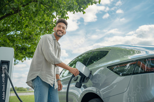 Happy man electric car charging station outdoor smile young adult male casual clothes green energy concept joyful happy man electric car charging station outdoor smile young adult male casual