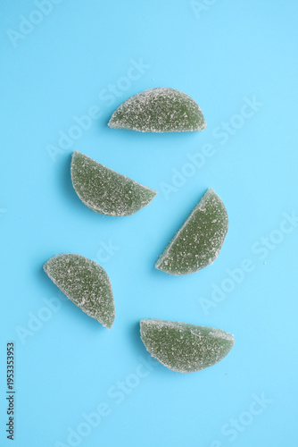 Green gummy candies float on a soft blue surface
