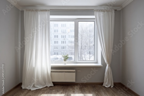 Bright room with white curtains frames a window overlooking a winter cityscape.