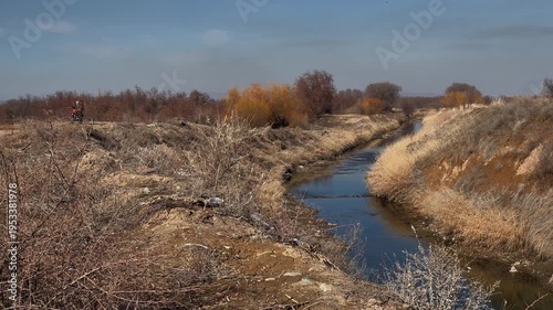 A lonely river, rural expanses, autumn landscape and a motorcycle passing by