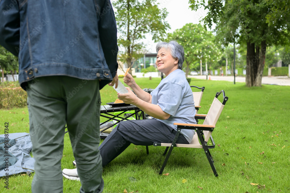Obraz premium Senior couple enjoying food during camping in a park