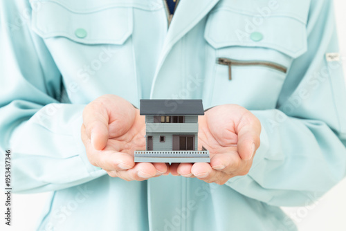 作業着を着た男性と家模型