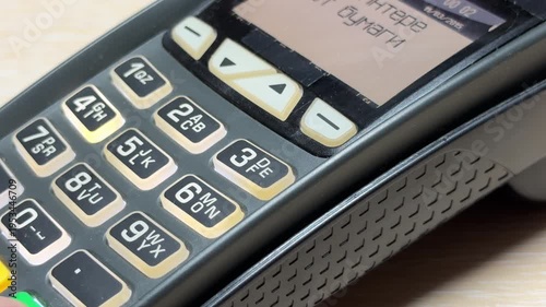 A person presses the tactile rubber buttons on a credit card terminal. Each key press triggers a short, high-pitched electronic beep and a soft plastic click.