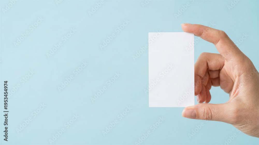 Obraz premium Blank business card mockup pinched between thumb and index finger on cold blue background 