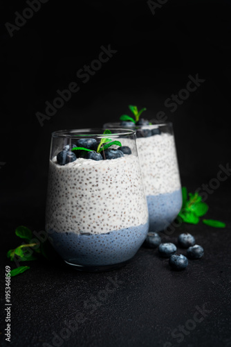 Chia pudding with blueberries on a dark background. Chia pudding, mint and blueberries on a black background. High quality photo