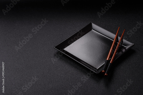 An empty ceramic square black plate with chopsticks for Asian food. An empty square plate