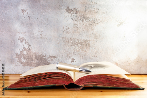 Bullet on a opened vintage book with red pages ona wooden desk, religious killings concept