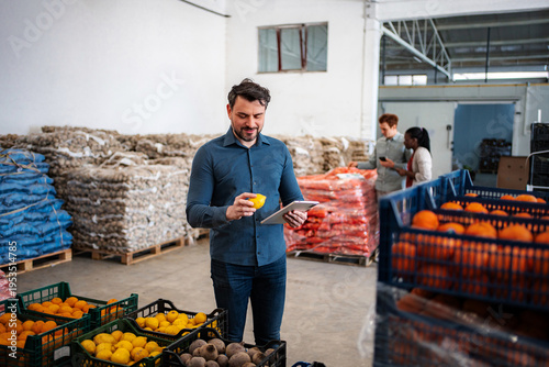 Φωτογραφία Produce warehouse worker inspecting fruit using digital tablet