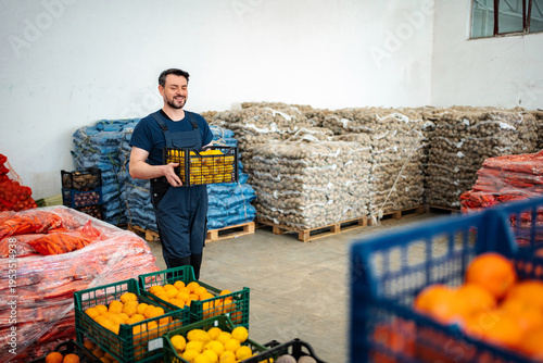 Foto Man smiling carrying a crate of fresh produce in warehouse
