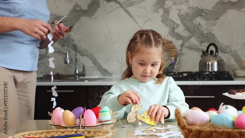 Mid shot of mother and her little daughter are cutting paper garlands in preparation for the Easter holiday