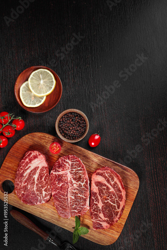Raw Beef Steaks on Cutting Board with Seasonings and Fresh Ingredients for Cooking