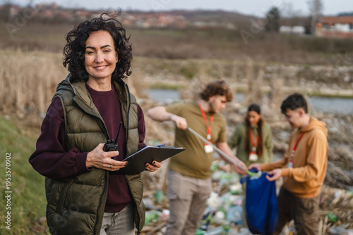 Photos Female volunteer organizer supervising river cleanup with young people