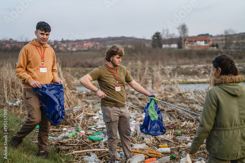 Canvas-taulu Volunteers cleaning plastic pollution from riverbank environment