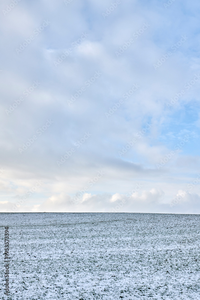 Fototapeta premium Snow, landscape and field with clouds, sky and environment for agriculture with cold weather. Winter, countryside and grass on farm, meadow and rural plain outdoor in nature with space in Iceland
