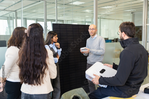 Office team collaborating with employee presenting solar panel battery