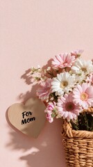 Soft pink daisies in a woven basket with a wooden heart gift for Mom on Mother's Day