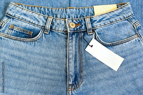 Blue jeans trousers with blank price tag paper photo front view full frame