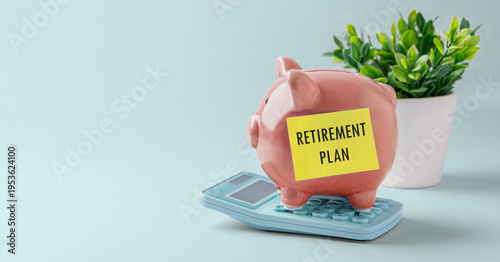 Retirement savings plan concept, Piggy bank on calculator with Retirement plan sticky note, small plant on blue background