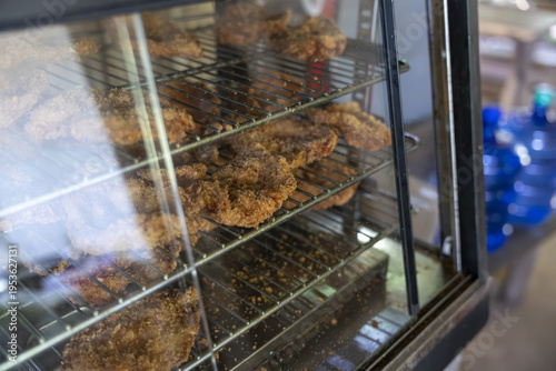 фотографія Fried chicken pieces resting wire racks inside warm glass display case creating