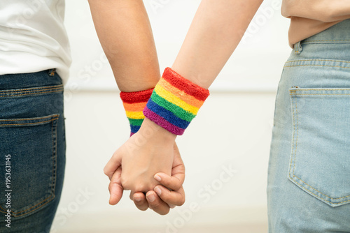 Photos Asian LGBT couple woman holding hand wearing rainbow wristband.