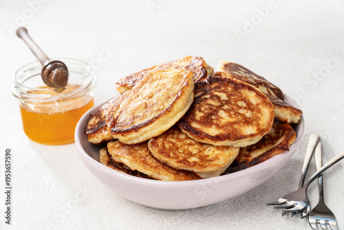 Homemade fluffy pancakes with honey, cozy brunch breakfast concept, comfort food stack on light background