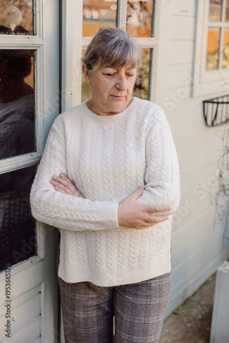 Mature woman with arms crossed looking concerned by house outdoors