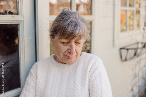 Mature woman looking down with sad thoughtful expression outdoors