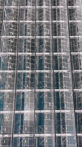 Vertical aerial top down view of a large modern glass greenhouse complex. Industrial agriculture and smart farming technology for sustainable food production