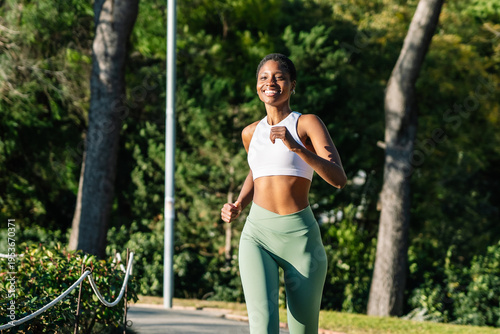 Happy black woman jogging for fitness in park