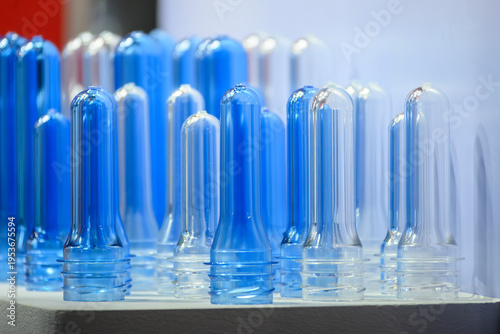 Close-up of a group of clear and blue PET plastic bottle preforms ready for the blow molding process.