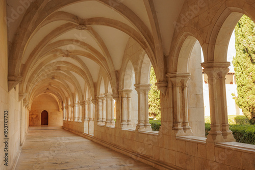 Tableau sur toile A long perspective view of a limestone Gothic corridor with vaulted ceilings and elegant stone arches in the European Monastery