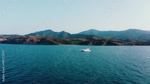 White Yacht Sailing on Calm Mediterranean Sea with Mountain Backdrop