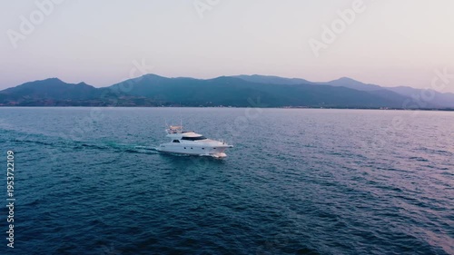 White Yacht with Golden Lights Sailing on Sea Against Mountain Range Dusk