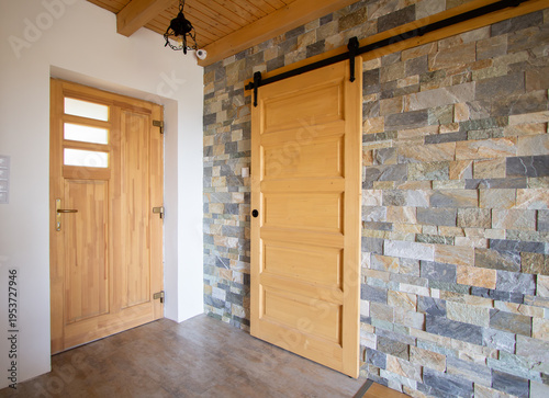 Top hung hanging wooden barn sliding door with a grey brick wall