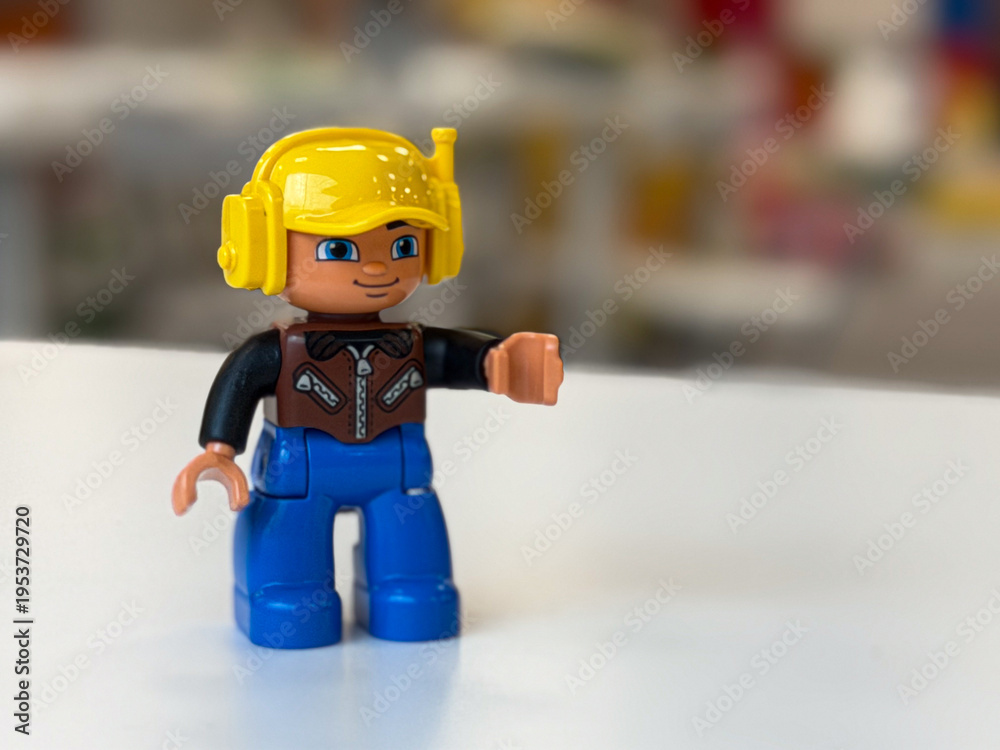 Fototapeta premium Yellow-helmet toy figure on white surface