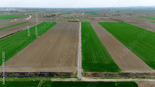 Aerial view of the patchwork of green and brown fields, divided by narrow paths, creating a geometric tapestry under a soft sky, Sremska Mitrovica, Vojvodina, Serbia.