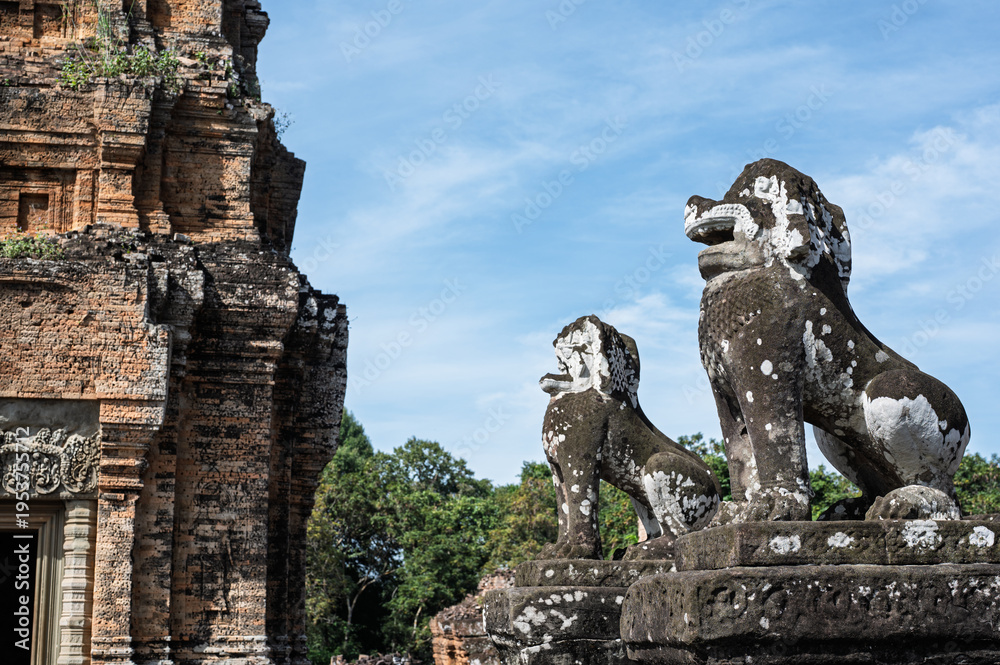 Obraz premium Close up of two weathered stone lion statues guarding entrance to ancient temple ruins in angkor archaeological park siem reap