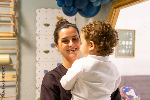 Educator smiling at young child in nursery