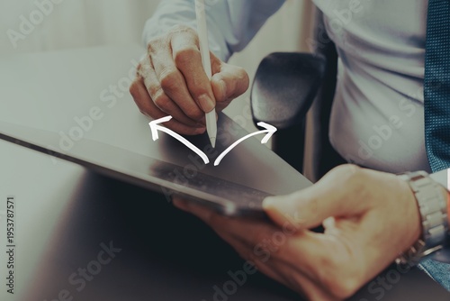 Quadro su tela Businessman using stylus on tablet with arrows indicating two possible directions, illustrating digital decision making and choosing between alternatives