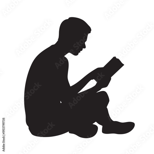 A man sits cross-legged on the floor reading a book quietly indoors.