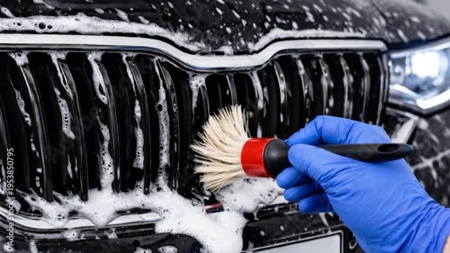 Car detailing process, cleaning radiator grille with soft brush and active foam soap.

