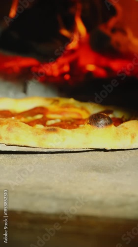 Experienced cook uses special pizza peel to rotate pizza inside stone oven. Chef rotates pizza to achieve uniform cooking. Vertical video